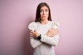 Young beautiful woman with blue eyes wearing casual white t-shirt over pink background shaking and freezing for winter cold with Royalty Free Stock Photo