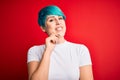 Young beautiful woman with blue fashion hair wearing casual t-shirt over red background looking confident at the camera smiling Royalty Free Stock Photo