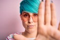 Young beautiful woman with blue fashion hair wearing fanny glasses with hearts with open hand doing stop sign with serious and