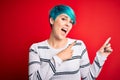 Young beautiful woman with blue fashion hair wearing striped sweater over red background smiling and looking at the camera Royalty Free Stock Photo