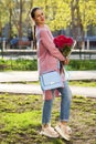 Young beautiful woman with a bouquet of red roses in spring park Royalty Free Stock Photo