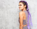 Young beautiful woman with braids posing in profile on a gray background in a fashionable summer outfit. Indoor. Royalty Free Stock Photo