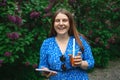 Young beautiful woman in bright blue dress holding plastic cold tea cup and looking at smartphone while walking at city Royalty Free Stock Photo