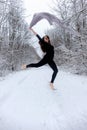 Young beautiful woman brown-haired girl in black ballet suit dances peak in snowy winter forest Royalty Free Stock Photo