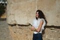 Young and beautiful woman, brunette, with curly hair and smiling, wearing a white shirt and jeans, with her arms crossed leaning Royalty Free Stock Photo