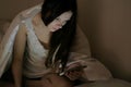 Young beautiful woman brunette looks at messages in her mobile phone in bed before sleeping. Royalty Free Stock Photo