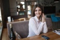 Young beautiful woman, brunette, sitting alone at a table in a cafe Royalty Free Stock Photo