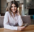 Young beautiful woman, brunette, sitting alone at a table in a cafe Royalty Free Stock Photo