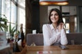 Young beautiful woman, brunette, sitting alone at a table in a cafe Royalty Free Stock Photo