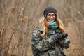 Young beautiful woman in camouflage outfit discovering nature in the forest with photo camera. Travel photography lifestyle Royalty Free Stock Photo