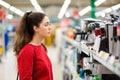 A young beautiful woman chooses kitchen gadgets in a home appliance store. Side view. The concept of consumerism