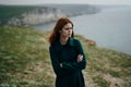 Young beautiful woman on a cliff of a mountain near the sea, the wind