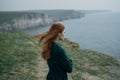 Young beautiful woman on a cliff of a mountain by the sea, wind, nature Royalty Free Stock Photo