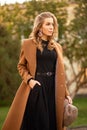 Young beautiful woman in coat posing on city street