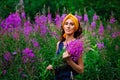 A young beautiful woman collects flowers in a field. A woman walks through a field of flowers. A bouquet of pink flowers of narrow