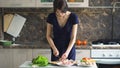 Young beautiful woman cook cutting the mushrooms on wooden board for pizza in the kitchen at home Royalty Free Stock Photo