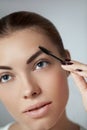 Young beautiful woman correcting shape of eyebrows.