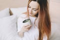 Young beautiful woman with cup of coffee or cacao in bed at home. Girl having breakfast in bed. Morning concept Royalty Free Stock Photo