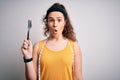 Young beautiful woman with curly hair doing diet holding fork and tape measure scared in shock with a surprise face, afraid and Royalty Free Stock Photo