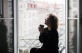 beautiful woman with curly hair drinking coffee near the open window Royalty Free Stock Photo