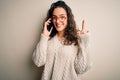 Young beautiful woman with curly hair having conversation talking on the smartphone surprised with an idea or question pointing Royalty Free Stock Photo