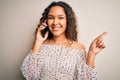 Young beautiful woman with curly hair having conversation talking on the smartphone surprised with an idea or question pointing Royalty Free Stock Photo