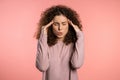 Young beautiful woman with curly hair having headache, pink studio portrait Royalty Free Stock Photo