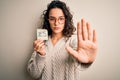 Young beautiful woman with curly hair holding reminder paper with yes word message with open hand doing stop sign with serious and Royalty Free Stock Photo