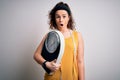 Young beautiful woman with curly hair holding weighing machine and tape measure scared in shock with a surprise face, afraid and Royalty Free Stock Photo