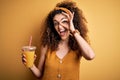 Young beautiful woman with curly hair and piercing drinking healthy orange juice with happy face smiling doing ok sign with hand Royalty Free Stock Photo