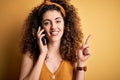 Young beautiful woman with curly hair and piercing having conversation talking on smartphone surprised with an idea or question Royalty Free Stock Photo