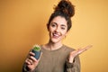 Young beautiful woman with curly hair and piercing holding pot with cactus plant very happy and excited, winner expression Royalty Free Stock Photo