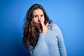 Young beautiful woman with curly hair wearing blue casual sweater over isolated background hand on mouth telling secret rumor, Royalty Free Stock Photo