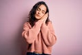 Young beautiful woman with curly hair wearing casual sweater over isolated pink background sleeping tired dreaming and posing with Royalty Free Stock Photo