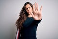 Young beautiful woman with curly hair wearing casual sweater over isolated white background doing stop sing with palm of the hand