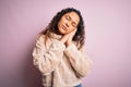 Young beautiful woman with curly hair wearing casual sweater standing over pink background sleeping tired dreaming and posing with Royalty Free Stock Photo