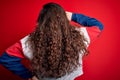 Young beautiful woman with curly hair wearing casual sweatshirt over isolated red background Backwards thinking about doubt with Royalty Free Stock Photo