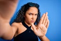 Young beautiful woman with curly hair wearing casual t-shirt making selfie by camera with open hand doing stop sign with serious Royalty Free Stock Photo