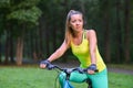 Young beautiful woman cycling on bicycle, summer park exercising Royalty Free Stock Photo