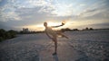 Young beautiful woman is dancing with fire wearing body suit on sunrise in the desert