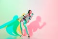 Young beautiful woman dancing hip-hop, street style isolated on studio background in neon light Royalty Free Stock Photo
