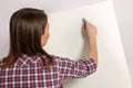 Young beautiful woman with dark brown hair writes something with bright blue chalk on white desk. Back to school or educating conc Royalty Free Stock Photo