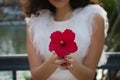 Young, beautiful woman with dark, curly hair and an upturned nose. The woman poses for the photo with an exotic red flower. The