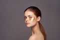 Young beautiful woman on a dark gray background in gold patches for groom, facial skin treatment Royalty Free Stock Photo