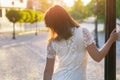 Young beautiful woman, dark-haired, stands with her back against the phonor in the street in the city center on a sunny day, in a