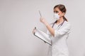 Young beautiful woman doctor in a respirator in a white coat on a light background Royalty Free Stock Photo