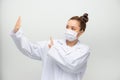 A young beautiful woman doctor in a white coat shows a stop gesture on white background. Say No virus disease Royalty Free Stock Photo