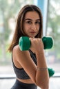 Young beautiful woman doing exercise with dumbbells while standing in front of window Royalty Free Stock Photo