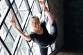 Young beautiful woman doing yoga asana natarajasana on large triangular window background