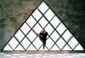 Young beautiful woman doing yoga asana toe pose variation on large triangular window background